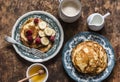 Delicious breakfast - cappuccino and pancakes with banana, raspberries, honey on a wooden background, top view