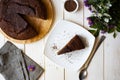 Delicious breakfast: chocolate cake on a wooden plate, a piece of chocolate cake on a white plate on a white table. Top Royalty Free Stock Photo