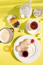 Delicious Breakfast with Cottage Cheese Pancakes, Oatmeal, Tea, Honey, Jam, Fruit on Yellow Table