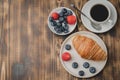 Delicious breakfast with cup of coffee and croissant with fresh berries on a wooden table. Top view and copy space Royalty Free Stock Photo