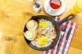 Breakfast skillet with eggs, ham, and vegetables served on rustic wooden table Royalty Free Stock Photo