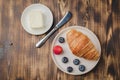 Delicious breakfast with fresh berries.Top view. Croissant with berries in white bowl and butter on wooden background