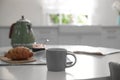 Delicious breakfast with croissant and cup of hot drink in kitchen Royalty Free Stock Photo