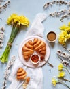 Delicious breakfast with fresh croissants, jam and coffee with spring flowers bouquet of daffodils on a light blue