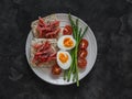 Delicious breakfast - loaves with lightly salted salmon, boiled egg, asparagus, cherry tomatoes on a dark background, top view