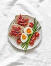 Delicious breakfast -loaves with lightly salted salmon, boiled egg, asparagus, cherry tomatoes on a light background, top view