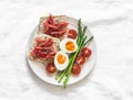 Delicious breakfast -loaves with lightly salted salmon, boiled egg, asparagus, cherry tomatoes on a light background, top view