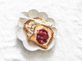 Delicious breakfast, snack - crispy toast with butter and cranberry jam on a light background, top view