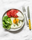 Delicious breakfast, snack, tapas - fried egg, ripe tomatoes, greek cheese, green salad on a light background, top view Royalty Free Stock Photo
