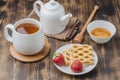 Delicious breakfast with tea, honey and wafers decorated with fresh strawberry on a wwoden table Royalty Free Stock Photo