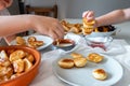 Delicious breakfast with tiny mini pancakes, cherries, apricots, jam on a white table. Small children hold pancakes in