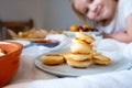 Delicious breakfast with tiny mini pancakes, cherries, apricots, jam on a white table. Small children hold pancakes in