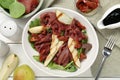 Delicious bresaola salad with sun-dried tomatoes, pear and balsamic vinegar served on white wooden table, flat lay