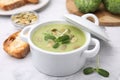 Delicious broccoli cream soup with pumpkin seeds on white marble table
