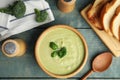 Delicious broccoli cream soup served on blue wooden table, flat lay