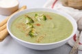 Delicious broccoli cream soup served on light table, closeup