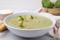 Delicious broccoli cream soup served on light table, closeup