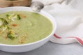 Delicious broccoli cream soup served on light table, closeup. Space for text