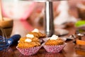 Delicious brown colored muffins with caramel sauce and cream topping, colorful cake in background, pastry concept Royalty Free Stock Photo