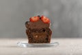 Delicious brown cupcake decorated with chocolate cream and berries on glass plate. Fresh muffins with butter glaze
