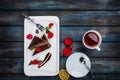 Delicious brownie cake with a cup of tea rose petals and forks on a white plate. Top view. Beautiful wooden background. Royalty Free Stock Photo