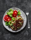 Delicious brunch - avocado, bacon sandwich and tomato lettuce salad on a dark background, top view Royalty Free Stock Photo