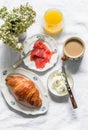 Delicious brunch, breakfast - cappuccino, croissant, cream cheese, smoked salmon, orange juice on a light background, top view