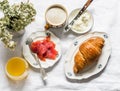 Delicious brunch, breakfast - cappuccino, croissant, cream cheese, smoked salmon, orange juice on a light background, top view