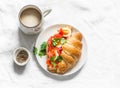 Delicious brunch, breakfast - coffee with cream and croissant sandwich with cream cheese, salmon and boiled egg on a light Royalty Free Stock Photo