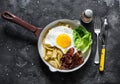 Delicious brunch, breakfast - potatoes hash, fried egg, bacon and green salad in a frying pan on a dark background, top view Royalty Free Stock Photo