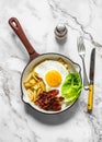 Delicious brunch, breakfast - potatoes hash, fried egg, bacon and green salad in a frying pan on a light background, top view Royalty Free Stock Photo