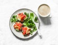 Delicious brunch, breakfast, snack - coffee with cream, salmon grain bread cream cheese sandwiches and arugula salad on a light