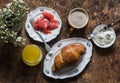 Delicious brunch - cappuccino, croissant, cream cheese, smoked salmon, orange juice on a wooden background, top view