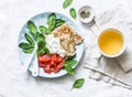 Delicious brunch - crepes with smoked salmon, spinach, sour cream and green tea on a light background