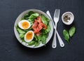 Delicious brunch - spinach, smoked salmon, soft boiled egg on a dark background, top view. Royalty Free Stock Photo