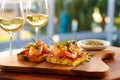 Delicious bruschetta with shrimps on a wooden board against the background of glasses with white wine