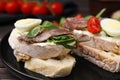 Delicious bruschettas with anchovies, cream cheese, arugula, eggs and tomatoes on table, closeup