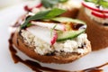 Delicious bruschettas with cream cheese, vegetables and balsamic vinegar on white plate, closeup