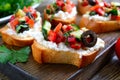 Delicious bruschettas with goat cheese and fresh vegetables. Crispy baguette slices with feta, tomatoes, cucumbers, peppers,