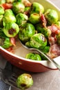 Delicious Brussels sprouts with bacon in baking dish on marble table, closeup