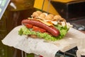 Delicious bubble waffle with fried egg and sausage slices on wooden board, closeup