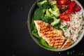Delicious buddha bowl with grilled chicken, fresh vegetables and rice on a dark background. Top view, above Royalty Free Stock Photo