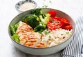 Delicious buddha bowl with grilled chicken, fresh vegetables and rice on a light background Royalty Free Stock Photo