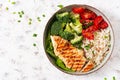 Delicious buddha bowl with grilled chicken, fresh vegetables and rice on a light background. Top view, above Royalty Free Stock Photo