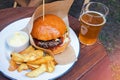 Delicious burger with french fries and a glass on beer on the wooden table Royalty Free Stock Photo