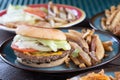 Delicious burger with roasted beef lettuce onions cheese and tomatoes next to fried potatoes Royalty Free Stock Photo