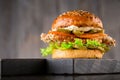 Delicious burger on wooden board on dark brown background