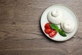 Delicious burrata cheese with basil and cut tomato on wooden table, top view. Space for text