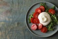 Delicious burrata cheese with tomatoes and arugula on grey wooden table, top view. Space for text