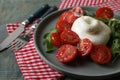 Delicious burrata cheese with tomatoes and arugula served on grey wooden table, closeup